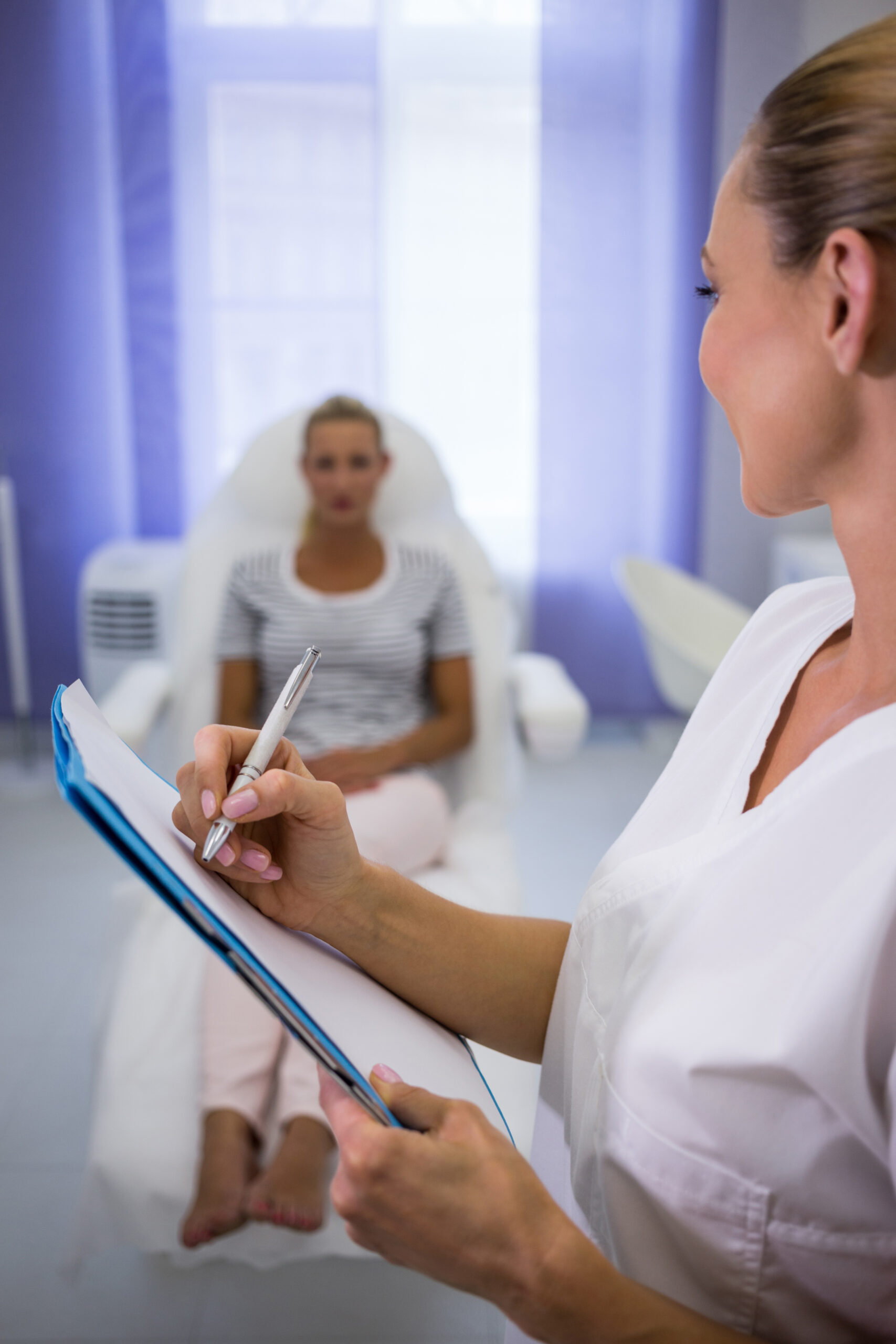 doctor writing medical reports while talking to patient at clinic